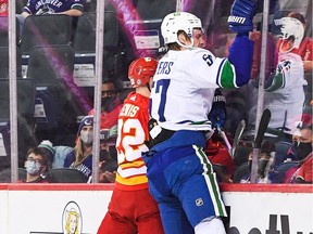 Tyler Myers checks Trevor Lewis of the Calgary Flames into the boards during an NHL game at Scotiabank Saddledome on January 29, 2022.