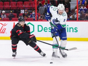 OTTAWA, ONTARIO - DECEMBER 01: Artem Zub #2 of the Ottawa Senators stickchecks J.T. Miller #9 of the Vancouver Canucks as he tried to play the puck during the first period at Canadian Tire Centre on December 01, 2021 in Ottawa, Ontario.