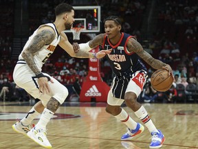 Houston Rockets guard Kevin Porter Jr. controls the ball as Denver Nuggets guard Austin Rivers defends during the first quarter at Toyota Center in Houston, Texas, Jan. 1, 2022.