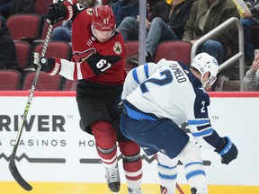 Winnipeg Jets defenceman Dylan DeMelo (2) checks Arizona Coyotes left wing Lawson Crouse (67) during the second period at Gila River Arena in Glendale, Ariz., on Jan. 4, 2022.