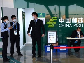 People chat in front of a China Post office at the press centre inside the Olympic "bubble" in Beijing, Thursday, Jan. 13, 2022.