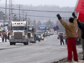 Protesters and supporters against a COVID-19 vaccine mandate for cross-border truckers cheer as a parade of trucks and vehicles pass through Kakabeka Falls outside of Thunder Bay, Ont. on Wednesday, January 26, 2022.