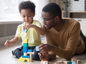 African father and son play with colourful toy blocks