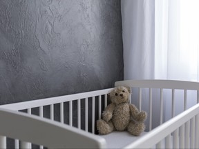 Shot of a teddy bear sitting in a crib