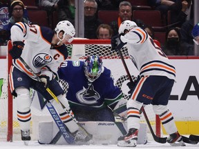 Vancouver Canucks goalie Spencer Martin stops Edmonton Oilers' Connor McDavid, left, and Kailer Yamamoto in Vancouver on Tuesday, Jan. 25, 2022.