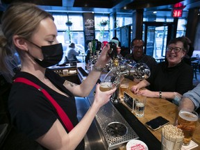Bartender Maggie Morris pours a pint of beer while sharing some new bar talk with Brigeen O'keefe and Javier Lee at Burgundy Lion restaurant Jan. 31, 2022.