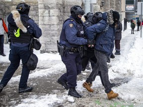 Eine Person wird von der Polizei von Ottawa in Gewahrsam genommen, als Beamte am 20. Februar 2022 den Kern der Innenstadt von „Freedom Convoy“-Demonstranten räumen.