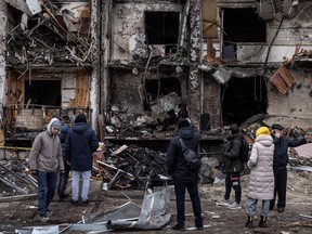 Die Menschen betrachten das Äußere eines beschädigten Wohnblocks, der am 25. Februar 2022 in Kiew, Ukraine, von einem Raketenangriff am frühen Morgen getroffen wurde.