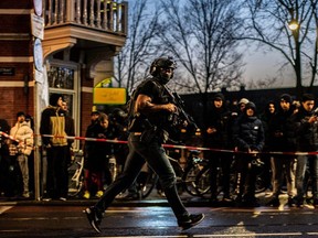 An armed member of the DSI (Dutch Special Intervention Service) arrives at Leidseplein during a hostage situation in an Apple Store in Amsterdam, Tuesday, Feb. 22, 2022.