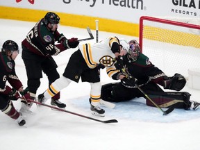 Coyotes goaltender Scott Wedgewood makes a save against Bruins winger Brad Marchand during third period NHL action at Gila River Arena in Glendale, Ariz., Jan. 28, 2022.