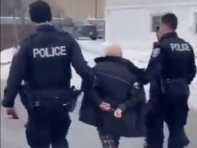 A screengrab from video of a handcuffed Gerry Charlebois with Ottawa Police officers on Monday, Feb. 7, 2022.