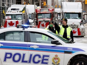 Police patrol a barricade while vehicles block downtown streets, as truckers and supporters continue to protest COVID-19 vaccine mandates, in Ottawa, Thursday, Feb. 3, 2022.
