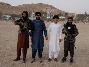 Parkbesucher posieren mit Taliban-Kämpfern aus der Provinz Wardak bei ihrem ersten Besuch in Kabul, während sie sich einen Tag frei nehmen, um den Vergnügungspark am Kabuler Qargha-Stausee am Stadtrand von Kabul zu besuchen, 8. Oktober 2021.