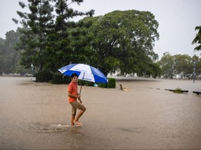 Ein Jugendlicher watet am 27. Februar 2022 durch eine überschwemmte Straße am Ufer des überlaufenden Brisbane River im West End im australischen Bundesstaat Queensland.