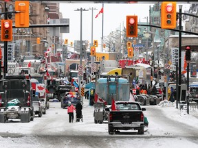 People walk between trucks parked near Parliament Hill, as truckers and supporters continue to protest COVID-19 vaccine mandates, in Ottawa on Friday, Feb. 4, 2022.