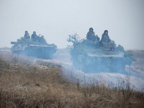 Ukrainian service members ride atop armoured vehicles during tactical drills at a training ground in an unknown location in Ukraine, in this handout picture released Tuesday, Feb. 22, 2022.