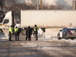 Polizisten bewachen eine Barrikade entlang der Straße, die zum Grenzübergang Ambassador Bridge in Windsor, Ontario, führt, Montag, 14. Februar 2022.