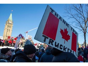 Unterstützer des Freedom Convoy stehen vor den Parlamentsgebäuden, während Trucker am 29. Januar 2022 in Ottawa an einem Konvoi teilnehmen, um gegen COVID-19-Impfstoffmandate für grenzüberschreitende Lkw-Fahrer zu protestieren.