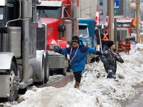 Children play on snow banks as truckers and their supporters continue to protest against the coronavirus disease (COVID-19) vaccine mandates, in Ottawa, Ontario, Canada, February 8, 2022.