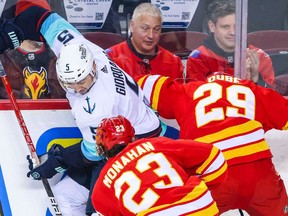 Seattle Kraken defenceman Mark Giordano battles for the puck with Flames forwards Dillon Dube and Sean Monahan on Saturday night at the Scotiabank Saddledome.