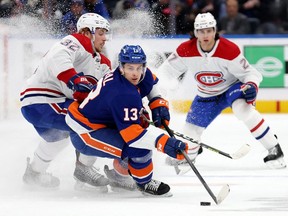 New York Islanders' Mathew Barzal (13) controls the puck against Canadiens' Rem Pitlick (32) and Alexander Romanov (27) during the first period at UBS Arena on Sunday, Feb. 20, 2022, in Elmont, N.Y.