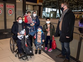Retired Canadian Forces Lt.-Col. Tony White greets Ahmad Seyar Sadiqi (L), aka Radar, as he arrives in Ottawa with his wife Tamana, their two-year-old daughter Ossna, and sons Mohammad, 4, and Sajad, 10, on Thursday, Feb. 11, 2022.