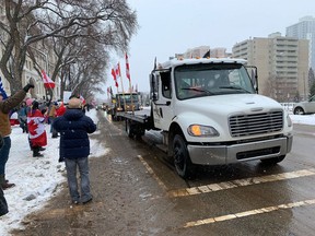 People line Edmonton's 109 Street near the Alberta legislature on Feb. 5, 2022, as a truck convoy drives by.