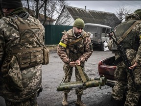 Ukrainian soldiers unload weapons from the trunk of an old car, northeast of Kyiv on March 3, 2022.