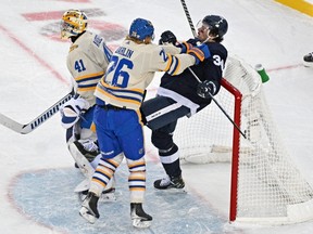 Buffalo Sabres defenceman Rasmus Dahlin (left) shoves Toronto Maple Leafs sniper Auston Matthews into the net behind goalie Craig Anderson during the Heritage Classic on Sunday at Tim Hortons Field.