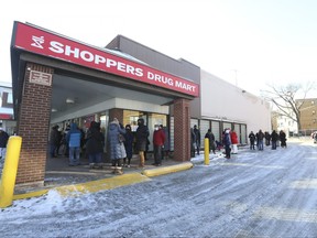 In this file photo taken on Dec. 19, 2021, people line up at the Shoppers Drug Mart at Humbertwon Shopping Centre in Toronto for a third dose of a COVID-19 vaccine.