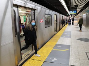 A woman wearing a mask exits a subway train in Toronto on March 17, 2020.