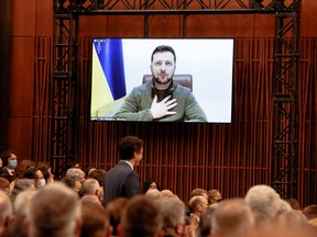 Members of the House of Commons and Senate listen as Ukrainian President Volodymyr Zelenskyy, who appears on a screen, addresses the Canadian parliament in Ottawa,, March 15, 2022.