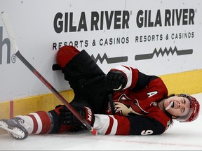 Clayton Keller of the Arizona Coyotes reacts in pain after crashing into the boards during the third period of the NHL game against the San Jose Sharks at Gila River Arena on March 30, 2022 in Glendale, Ariz.