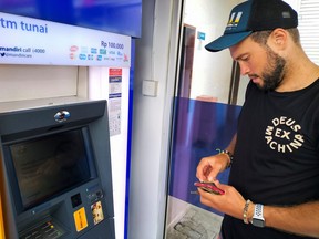 Konstantin Ivanov, a 27-year-old Russian who is in Bali, holds his cards as he tries to withdraw money from his Russian bank account at a cash machine in Kuta, Bali, Indonesia, March 8, 2022.