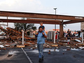Arturo Ortega and his son Kaysen Ortega, 2, survey the damage to a shopping centre after a tornado in a widespread storm system touched down in Round Rock, Texas, March 21, 2022.