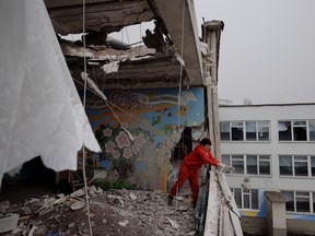 A woman clears debris from a school that was damaged by shelling in Kharkiv as Russia's attack on Ukraine continues March 27, 2022.