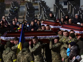People attend the memorial and funeral service for three fallen Ukrainian Army service men following the Russian invasion, during a ceremony in Lviv, Ukraine, Friday, March 11, 2022.