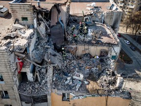 Eine Luftaufnahme zeigt Feuerwehrleute, die in den Trümmern eines Wohngebäudes arbeiten, das am 17. März 2022 in Kiew von den Trümmern einer abgeschossenen Rakete getroffen wurde.