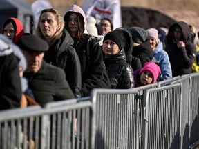 Refugees wait for a train after crossing the Ukrainian border into Poland, at the Medyka border crossing, Thursday, March 10, 2022.