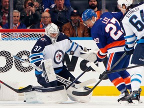 Connor Hellebuyck (37) of the Winnipeg Jets makes the first period save on Anders Lee (27) of the New York Islanders at the UBS Arena on March 11, 2022 in Elmont, N.Y.