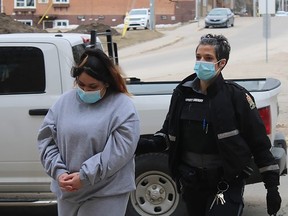 Latisha Grumbo, left, is seen being led into Court of Queen's Bench in Prince Albert, Sask., by an unidentified sheriff on Wednesday, April 27, 2022.