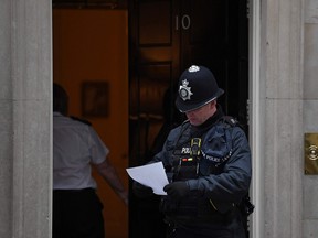 A police officer holds a piece of paper as he leaves 10 Downing Street, the official residence of Britain's Prime Minister, in London on January 25, 2022.