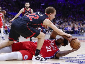 Philadelphia 76ers' Joel Embiid (right) battles from the floor for the ball with Raptors' Malachi Flynn during the first quarter of Game 2 of their Eastern Conference first-round series at Wells Fargo Center on Monday, April 18, 2022 in Philadelphia.