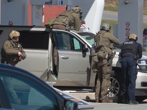 RCMP-Beamte bereiten sich darauf vor, am Sonntag, den 19. April 2020, eine Person an einer Tankstelle in Enfield, NS, in Gewahrsam zu nehmen.