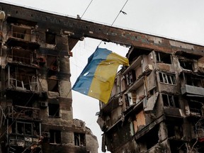 Eine Ansicht zeigt eine zerrissene Flagge der Ukraine, die an einem Draht vor einem während des Konflikts zwischen der Ukraine und Russland zerstörten Wohnhaus in der südlichen Hafenstadt Mariupol, Ukraine, am Donnerstag, dem 14.
