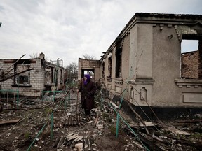 Hanna Chaika, 80, walks by her neighbour's house, that according to her was hit by rockets, amid Russia's invasion of Ukraine, in Ozera, Kyiv region, Saturday, April 23, 2022.