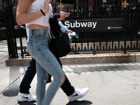 People walk by a subway stop in a busy midtown Manhattan on April 13, 2022 in New York.