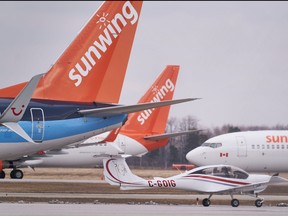 A small plane taxis past Boeing 737s belonging to Canadian Vacation air carrier Sunwing sit on the tarmac at Waterloo International Airport in Waterloo, Ont., on March 24, 2020.