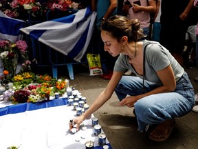 A woman lights a candle outside a bar which was the site of a fatal shooting attack in Tel Aviv, Israel, Friday, April 8, 2022.