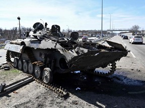 Cars drive past a burnt Russian armoured personnel carrier on a road west  of Kyiv, Thursday, April 7, 2022, during Russia's military invasion launched on Ukraine.